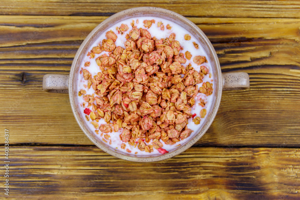 Granola with milk in bowl on wooden table. Top view. Healthy breakfast concept Granola with milk in bowl on wooden table. Top view. Healthy breakfast concept