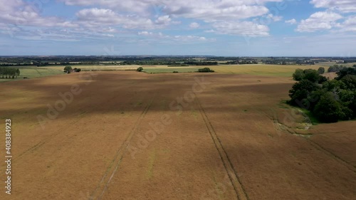 Descending drone shot flying backwards over a field with cloud shadows moving. 4k