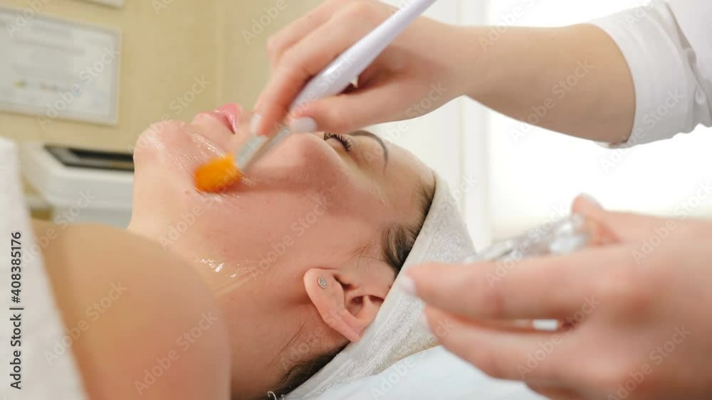Beauty clinic. Young woman gets professional facial anti-aging procedure. Beautician spreads gel mask on female face with brush. face renovation concept. beautician applies conductive gel. 4 k video Beauty clinic. Young woman gets professional facial anti-aging procedure. Beautician spreads gel mask on female face with brush. face renovation concept. beautician applies conductive gel. 4 k video