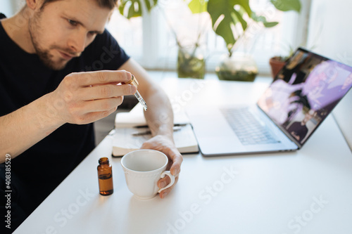Vitamins and supplements. Hand holding pipette of Hemp herbal oil. Close up man uses CBD oil. Medical cannabis essence. Healthy lifestyle use medical essential tincture for better skin