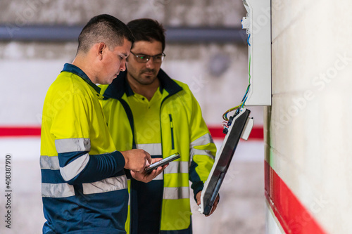 Male programmers working on electric meter in auto repair shop