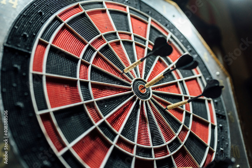 Black and red dartboard with darts