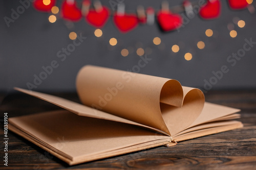 Heart made from book sheets in lights, love and valentine concept on a wooden table