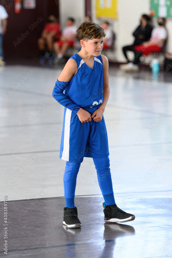 Naklejka premium Young athletic boy playing in a game of basketball