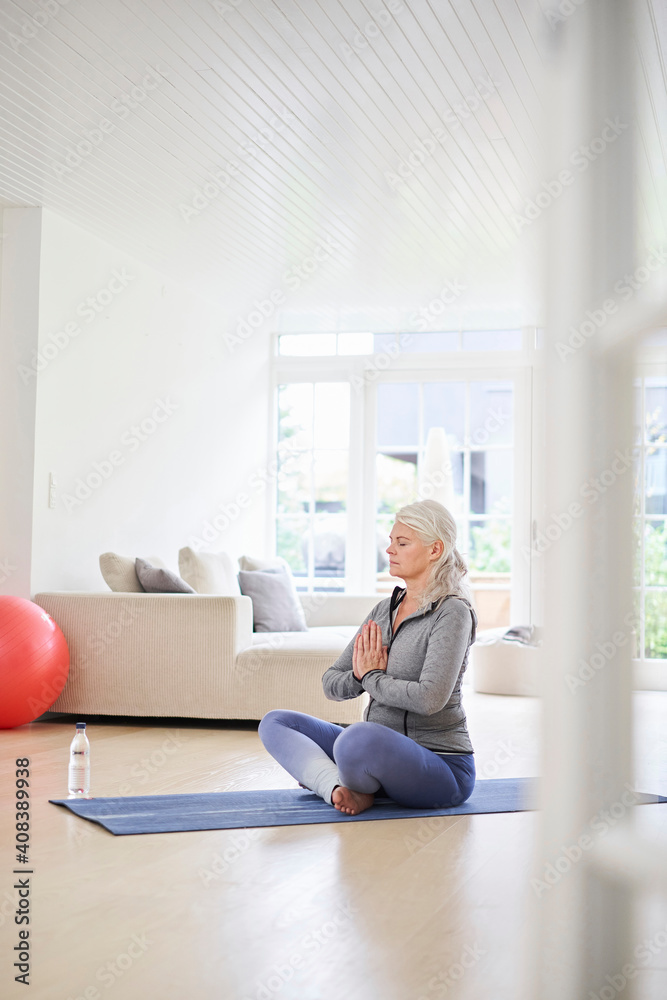 Senior woman with eyes closed meditating in living room Senior woman with eyes closed meditating in living room