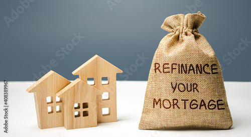 Money bag with the inscription Refinance your mortgage and miniature houses. Real estate, finance and business concept. Interest rates. Property financing concept photo