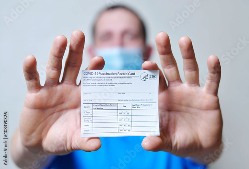 male is holding a vaccination record card and corona virus vaccine vials. Passport of immunity to the coronavirus in the hands of a male. Health passport as proof of recovery from COVID-19.