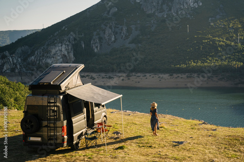 Woman looking at lake while standing by camper van during vacation photo