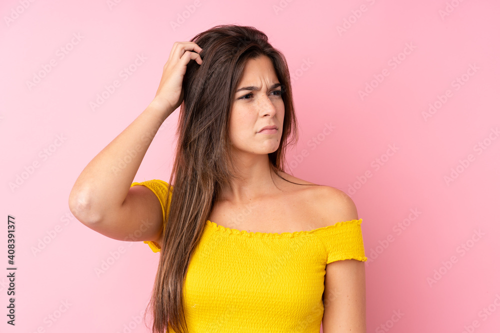 Teenager Brazilian girl over isolated pink background having doubts while scratching head Teenager Brazilian girl over isolated pink background having doubts while scratching head