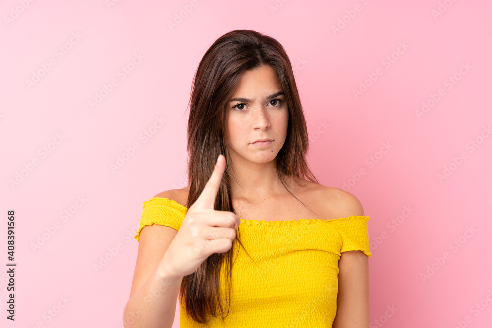 Teenager Brazilian girl over isolated pink background frustrated and pointing to the front Teenager Brazilian girl over isolated pink background frustrated and pointing to the front