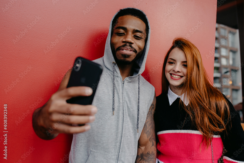 Smiling multi ethnic friends taking selfie by red backdrop Smiling multi ethnic friends taking selfie by red backdrop