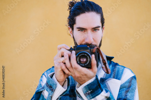 Tourist standing with camera against yellow wall photo