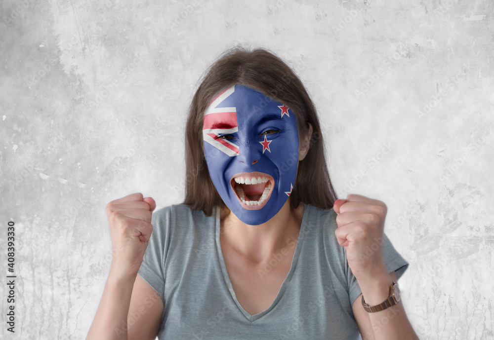 Young woman with painted flag of New Zealand and open mouth looking energetic with fists up Young woman with painted flag of New Zealand and open mouth looking energetic with fists up