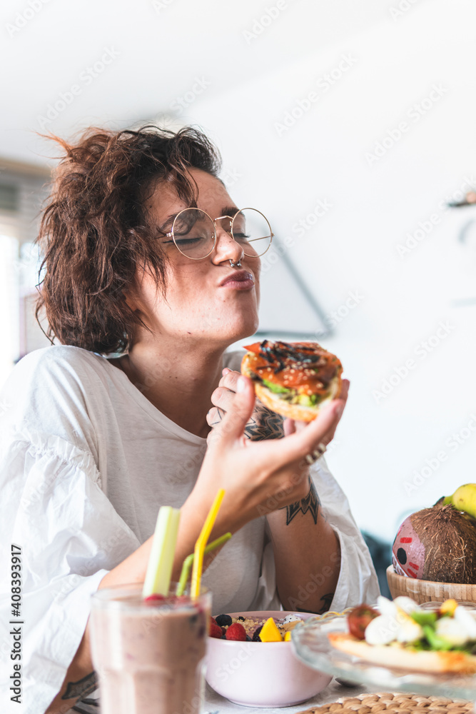 Portrait of young woman wearing eyeglasses and nose ring eating breakfast Portrait of young woman wearing eyeglasses and nose ring eating breakfast