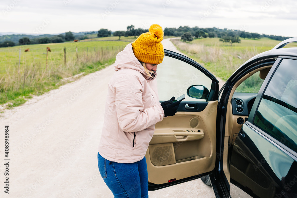 woman with a cold face, looking at her cell phone, with the car stopped and the driver's door open woman with a cold face, looking at her cell phone, with the car stopped and the driver's door open