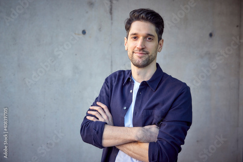 Mid adult businessman smiling while standing with arms crossed against wall photo