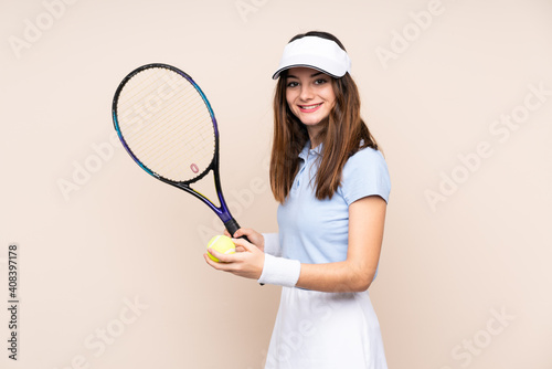 Young caucasian woman isolated on beige background playing tennis © luismolinero