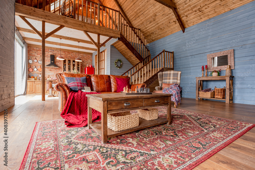 Naklejka premium cozy all wooden interior of a country house in a wooden design. spacious living room with kitchen area with large windows. bedroom on the second floor.