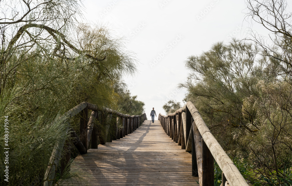 woman walking along a long wooden boardwalk