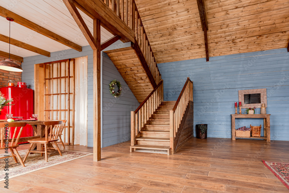 cozy all wooden interior of a country house in a wooden design. spacious living room with kitchen area with large windows. bedroom on the second floor. cozy all wooden interior of a country house in a wooden design. spacious living room with kitchen area with large windows. bedroom on the second floor.