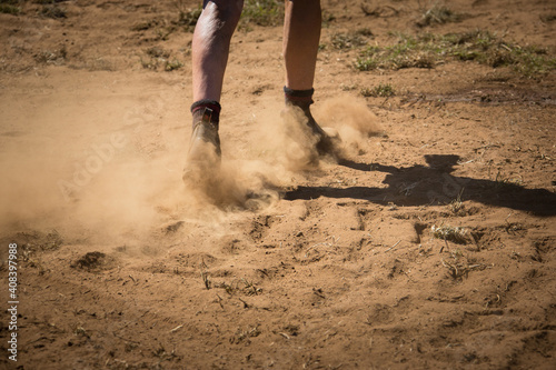 Workboots walking on dusty dry ground photo