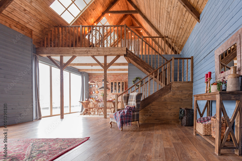 cozy all wooden interior of a country house in a wooden design. spacious living room with kitchen area with large windows. bedroom on the second floor. cozy all wooden interior of a country house in a wooden design. spacious living room with kitchen area with large windows. bedroom on the second floor.