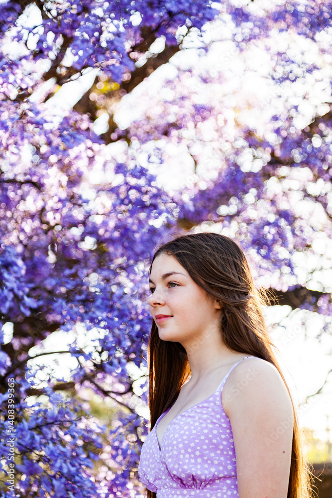 Teen girl profile portrait with bokeh purple jacaranda flowers in background