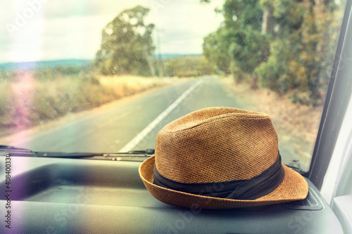hat on the dashboard of a car on a road trip, with light leak