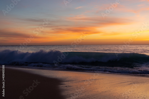 gorgeous colorful sunset over the ocean and beach with gentle waves lapping at the shore