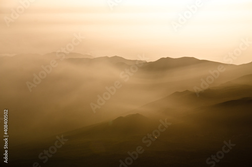 Fototapeta Naklejka Na Ścianę i Meble -  Sun beams passing through dawn mist with silhouettes of mountains, ridges and peaks, Tenerife, Canarian Islands