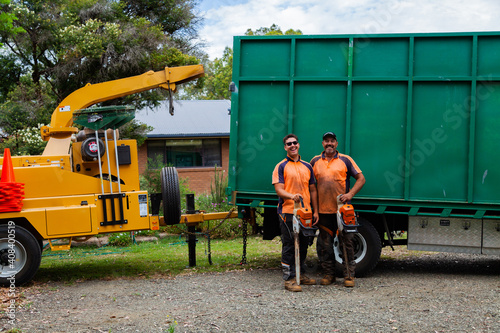 Portrait of a team of men who are tree felling lumberjacks with their chainsaws in front of truck photo