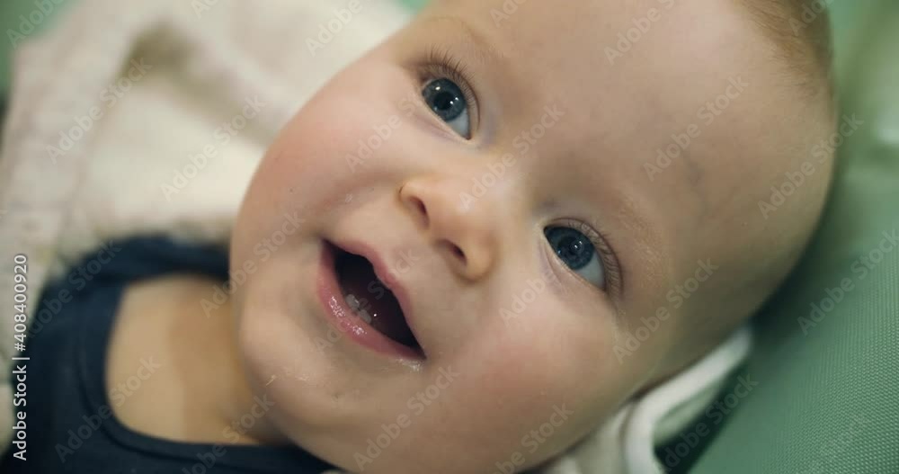 Close portrait of happy, blue-eyed infant smiling with two teeth Close portrait of happy, blue-eyed infant smiling with two teeth