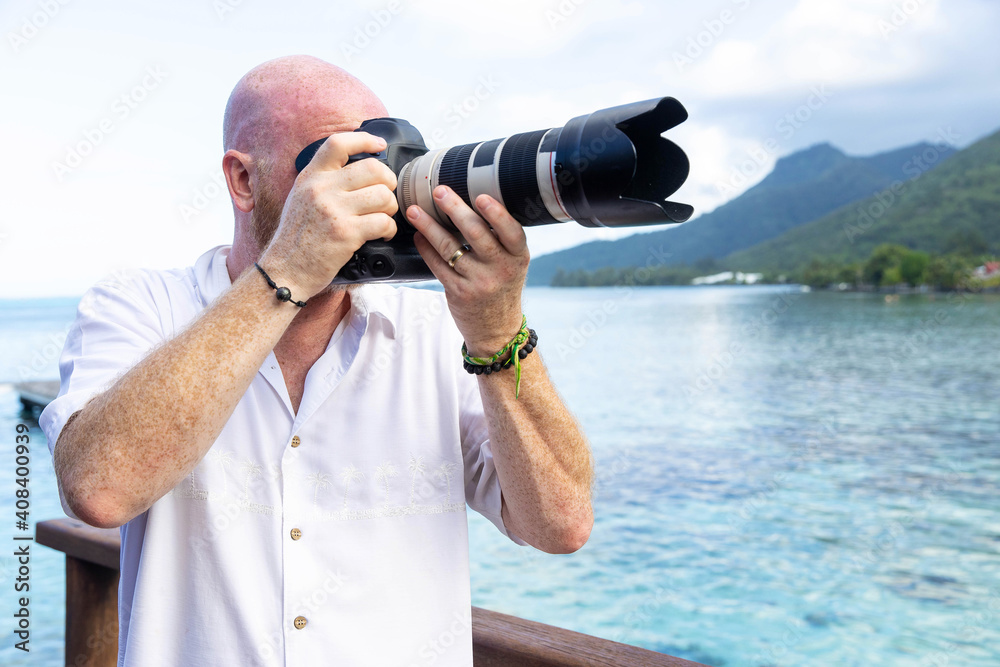 Obraz premium Man taking photos with digital camera outside while traveling at a tropical island