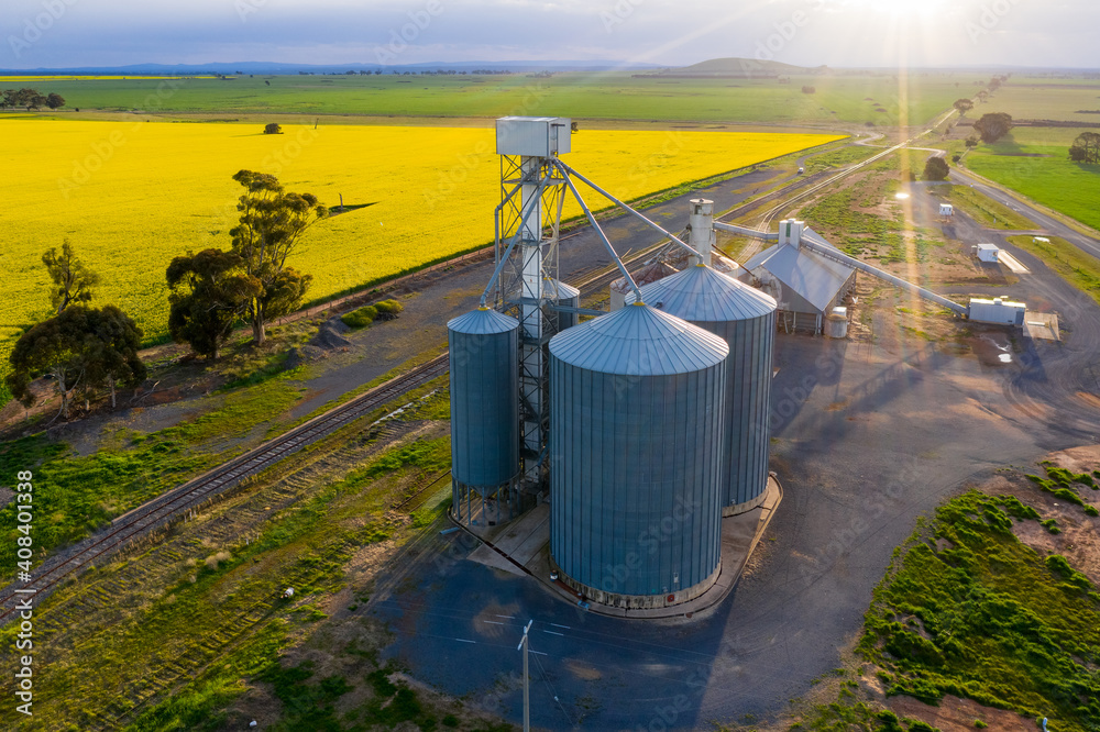 Aerial view of a grain silo along side a railway line and a canola field Aerial view of a grain silo along side a railway line and a canola field