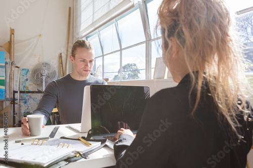 Young creative guy and girl sharing a co-working space
