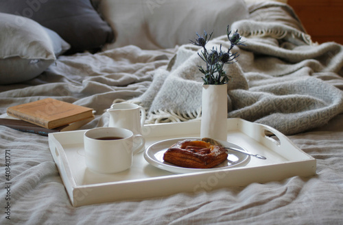 Breakfast tray on bed with grey linen and books photo