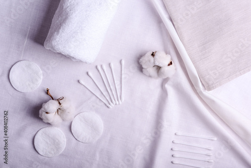 white cotton flowers and clean towels, cotton pads, sticks, flat lay. Natural cotton fabric texture