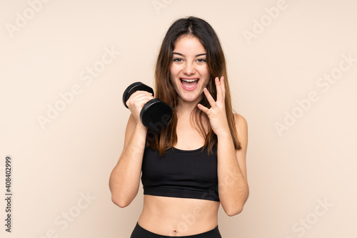 Young sport woman making weightlifting isolated on beige background with surprise facial expression