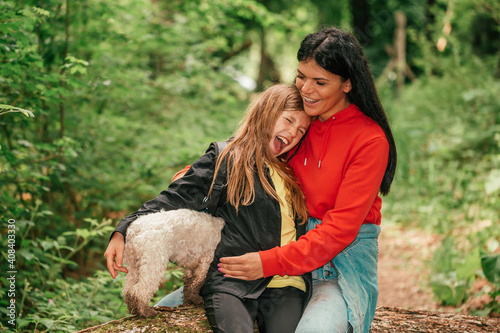 Mother, her cute daughter and dog having fun in a spring forest.