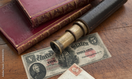 Close up of antique telescope, books and banknote photo