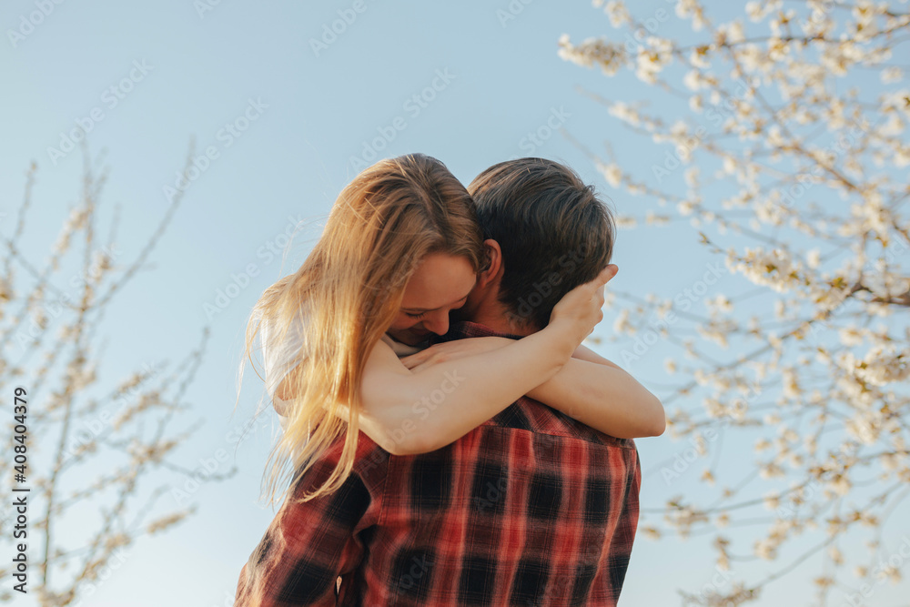 Loving couple is hugging near blossoming tree on a background of spring blue sky. Loving couple is hugging near blossoming tree on a background of spring blue sky.