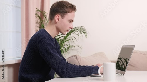 Young man sitting at home with laptop working online. Working as a freelancer or during a pandemic.