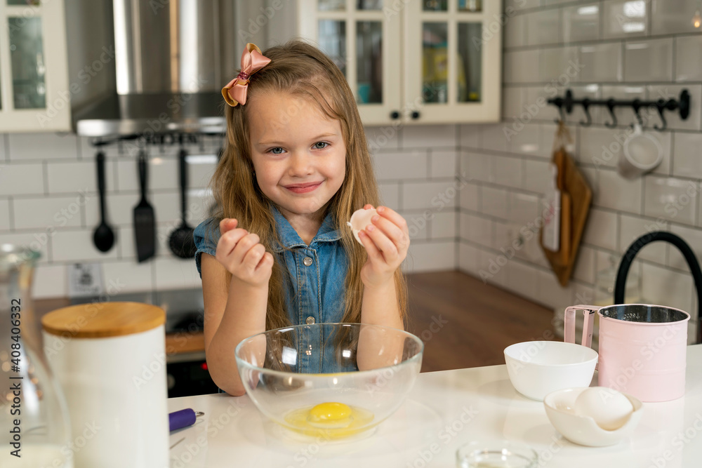 making breakfast, kids. smiling girl holding an egg shell in her hand. making breakfast, kids. smiling girl holding an egg shell in her hand.