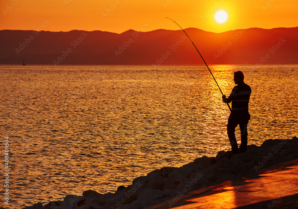 Fisher man with fishing rod on the beach