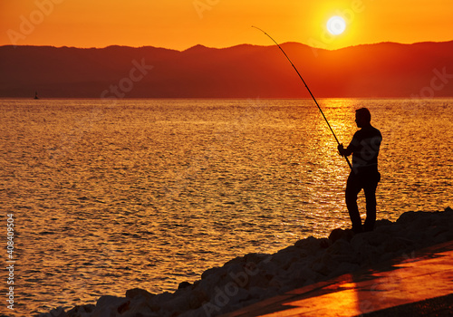 Fisher man with fishing rod on the beach