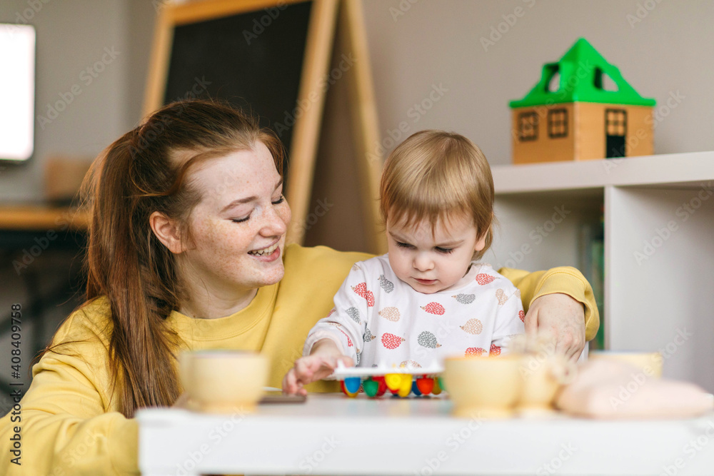 Early childhood learning. Mother and child play with wooden beads and cups, teaching colors and developing fine motor skills Early childhood learning. Mother and child play with wooden beads and cups, teaching colors and developing fine motor skills
