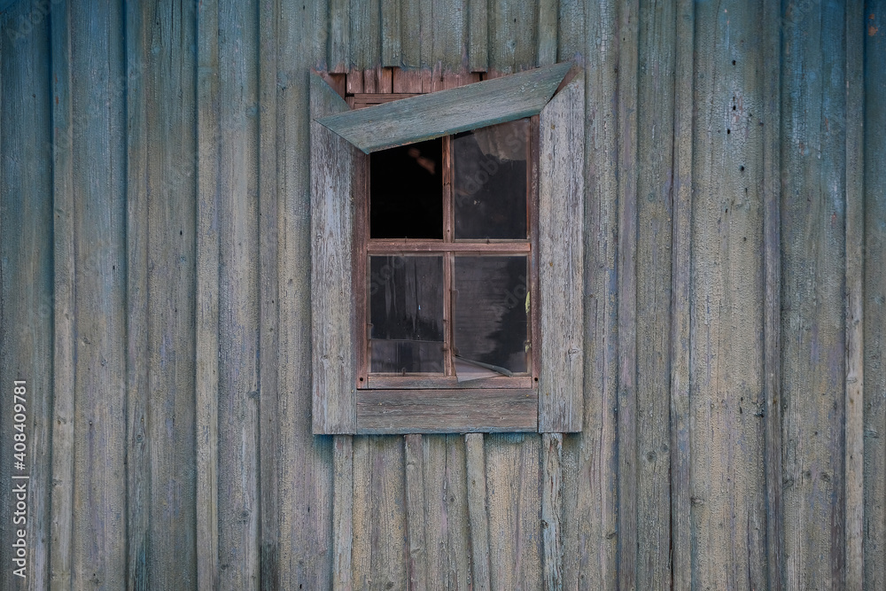 A small wooden window with broken glass and a rickety skirting board against the old wooden wall. A small wooden window with broken glass and a rickety skirting board against the old wooden wall.