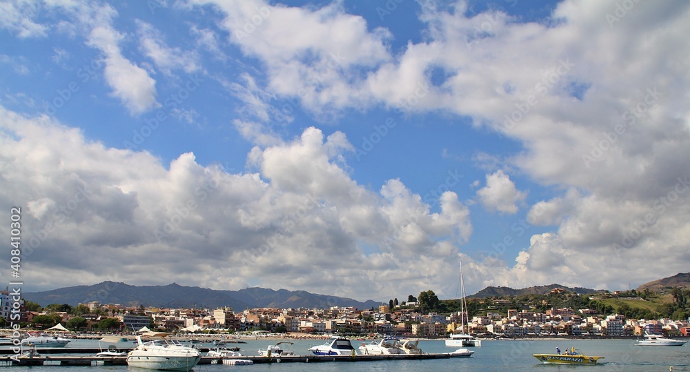 mountain view over the sea, a lot of dense white clouds above them, mountains descending into the sea, boats at sea, Sicily