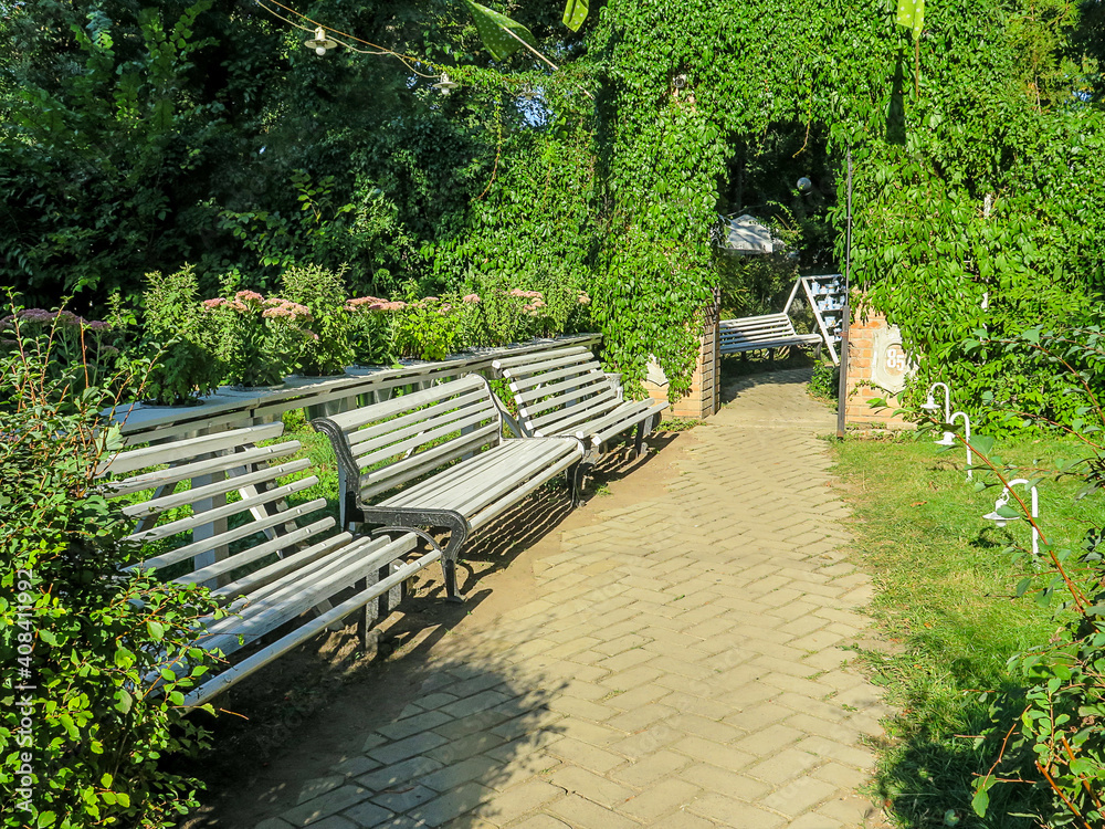 Empty bench on the street outside in the summer park. Urban background. Rest and relaxation
