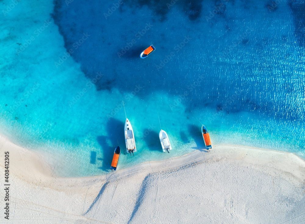 Aerial view of the yachts and fishing boats on tropical sea coast with white sandy beach at sunset in summer. Zanzibar, Africa. Colorful landscape with boats, transparent blue water. Top view. Travel - obrazy, fototapety, plakaty 